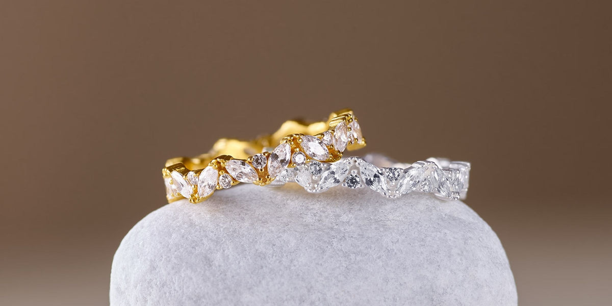 Vergoldeter und silberfarbener Ring mit funkelnden Zirkonia-Steinen aus der BERND WOLF Kollektion, präsentiert auf einer hellen Schmuckbasis.